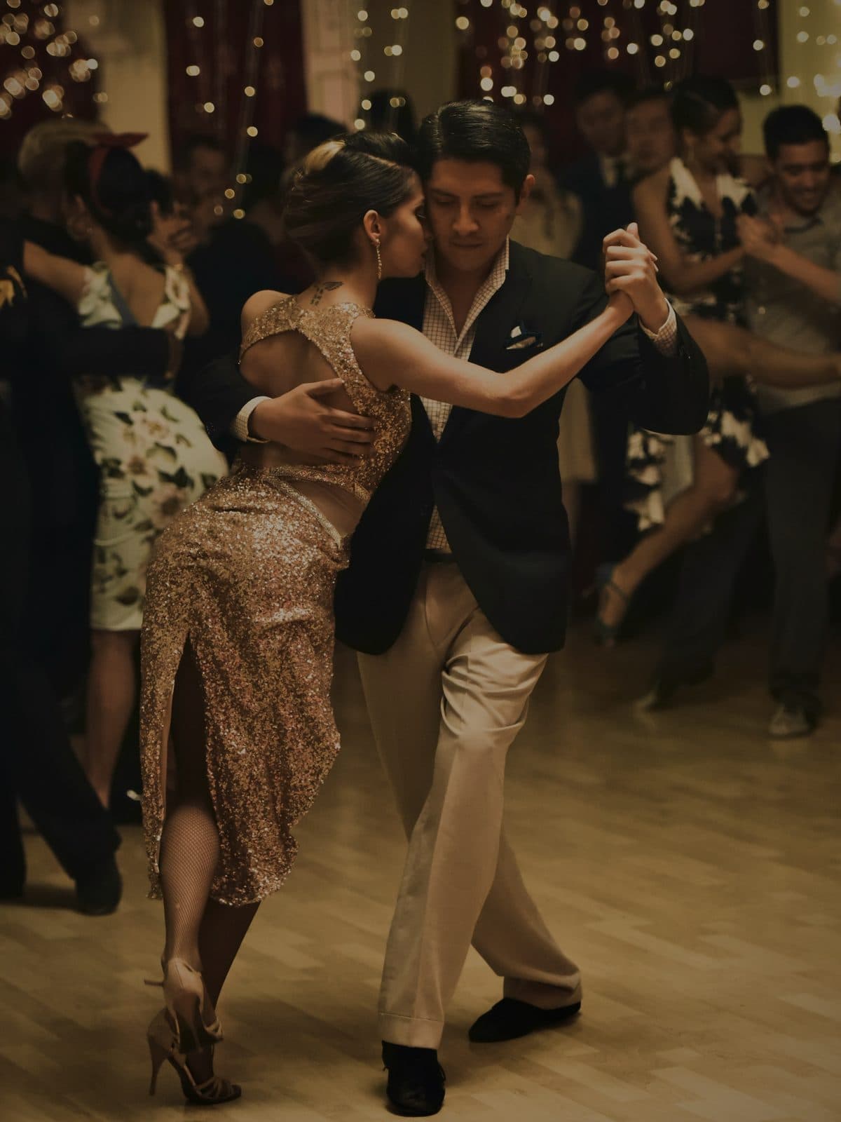 A full floor of couples dancing together under string lights